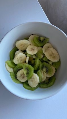 a white bowl filled with sliced kiwis on top of a table