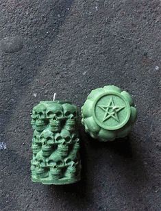 two green candles with skulls on them sitting on the ground in front of a star