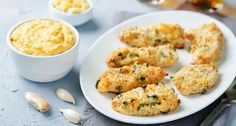 some food is sitting on a white plate next to garlic and sauces in small bowls