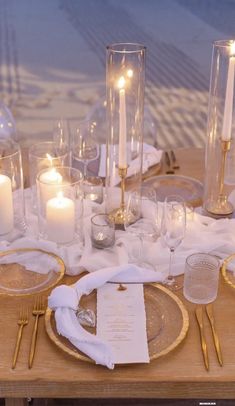 the table is set with candles, plates and napkins