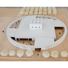 a model of a building made out of wood and white plastic pieces on a wooden table