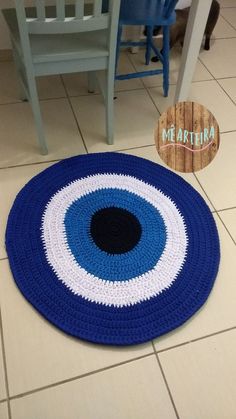 a blue and white crocheted rug sitting on the floor next to a chair