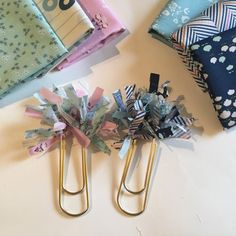 two paper clips sitting next to each other on top of a white table covered in fabric