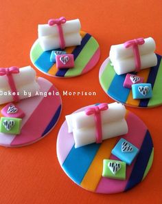 three cakes decorated with colorful fondant and bows on plates, one is shaped like a cake