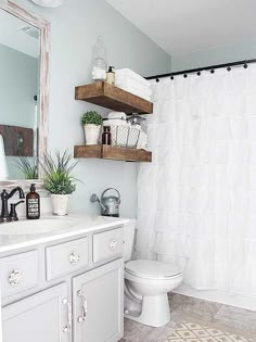 a bathroom with a white toilet sitting next to a bath tub under a mirror above a sink