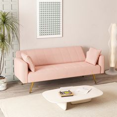 a living room with a pink couch and white coffee table in front of the wall