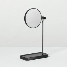 a black stand with a round mirror on it