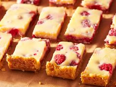 raspberry cheesecake bars are lined up on a cutting board and ready to be eaten