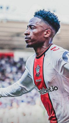 a soccer player with his arms out in front of the camera and looking at the ball