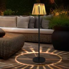 a floor lamp sitting on top of a table next to a couch