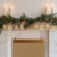 a decorated mantle with candles and greenery