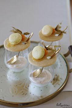 small desserts are arranged in glass cups on a plate with spoons and forks