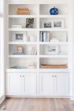 a white bookshelf filled with lots of books on top of wooden flooring