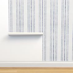 an empty room with striped wallpaper and a white shelf on the floor next to it