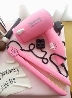 a pink birthday cake with hair dryers and other items