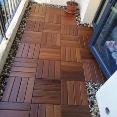 a wooden floor next to a potted plant on the side of a building with rocks and gravel