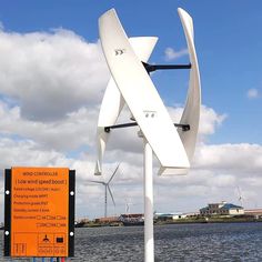 a white wind turbine sitting next to a body of water