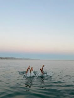 two people are swimming in the ocean with their feet up and one is upside down