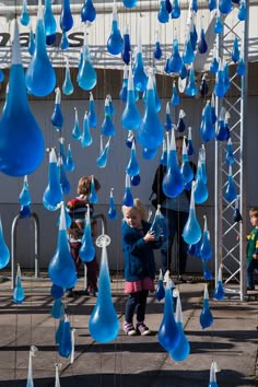 a group of children playing with blue glass raindrops hanging from the side of a building