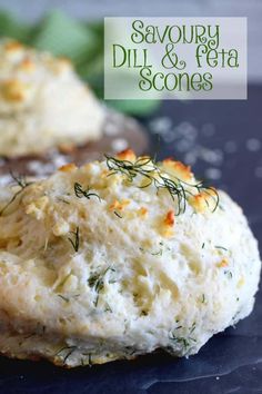 two biscuits covered in cheese and herbs on top of a black surface with the words savory dill & feta scones