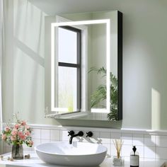 a white sink sitting under a bathroom mirror next to a vase with flowers in it