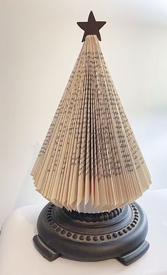 an origami christmas tree made out of old book pages with a star on top