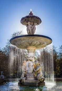 the fountain has two statues on it and is surrounded by water spouting from its sides