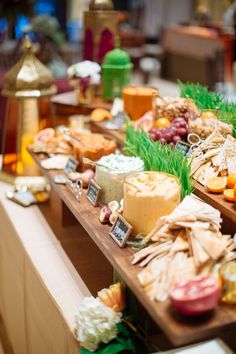 a table topped with lots of different types of cheeses and fruit on top of wooden boards