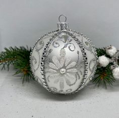 a white ornament sitting on top of a table next to some pine branches