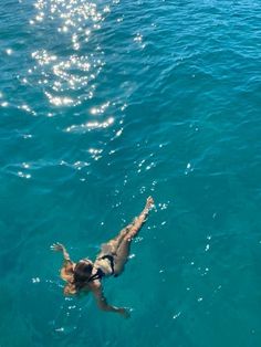 a woman swimming in the ocean with her back to the camera