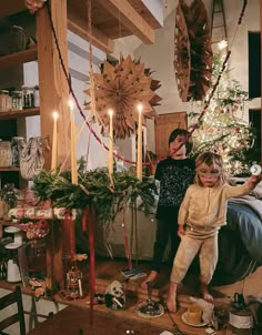 two women and a child standing in front of a christmas tree with candles on it