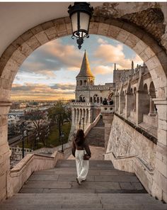 a woman walking up some stairs towards a castle