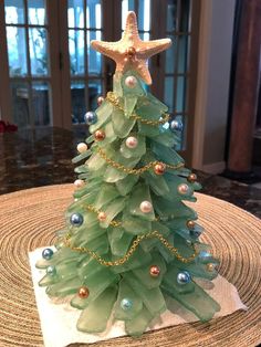 a small green christmas tree on top of a table next to a starfish ornament