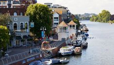 there are many boats that are docked in the water near some buildings on the other side of the river