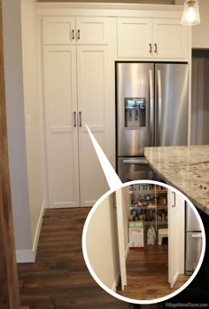 an open refrigerator in a kitchen with white cabinets and wood flooring next to it