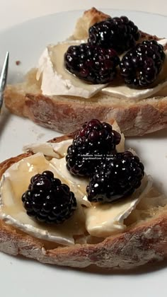 two pieces of bread topped with cream and blackberries