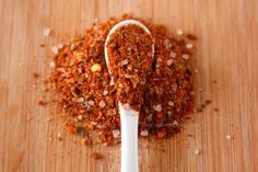 a spoon full of spices sitting on top of a wooden table