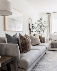 a living room filled with lots of furniture and pillows on top of a rug in front of a window