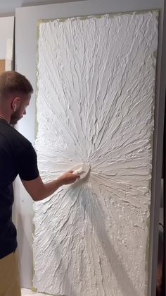 a man is working on a large piece of art that looks like an abstract painting