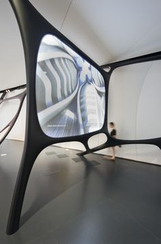 a person walking past a large mirror in an art gallery with black and white designs on it