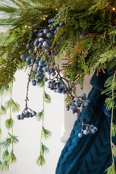 a christmas tree with blue berries hanging from it's branches