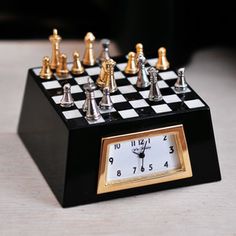 a clock with chess pieces sitting on top of it