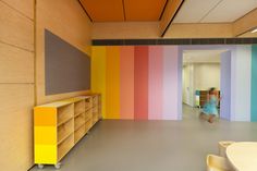 an empty room with multicolored walls and furniture