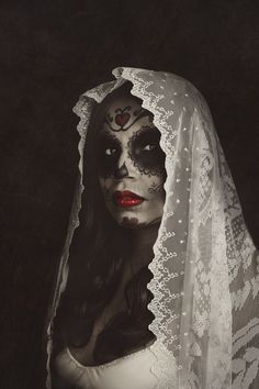 a woman with makeup on her face and veil over her head, wearing white lace