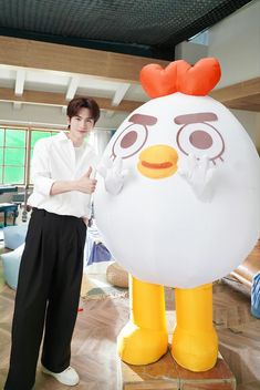 a man standing next to an inflatable chicken