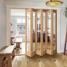 an open room with wooden floors and mirrors on the doors, in front of a dining table