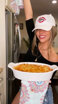 a woman holding up a large casserole dish in front of her face and wearing a white hat