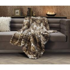 an animal print blanket on a couch in a living room with two pillows and a candle