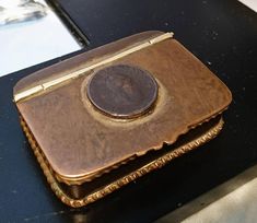 an old metal box sitting on top of a black table next to a glass bottle