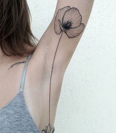 a woman's arm with a single flower tattoo on the back of her left arm